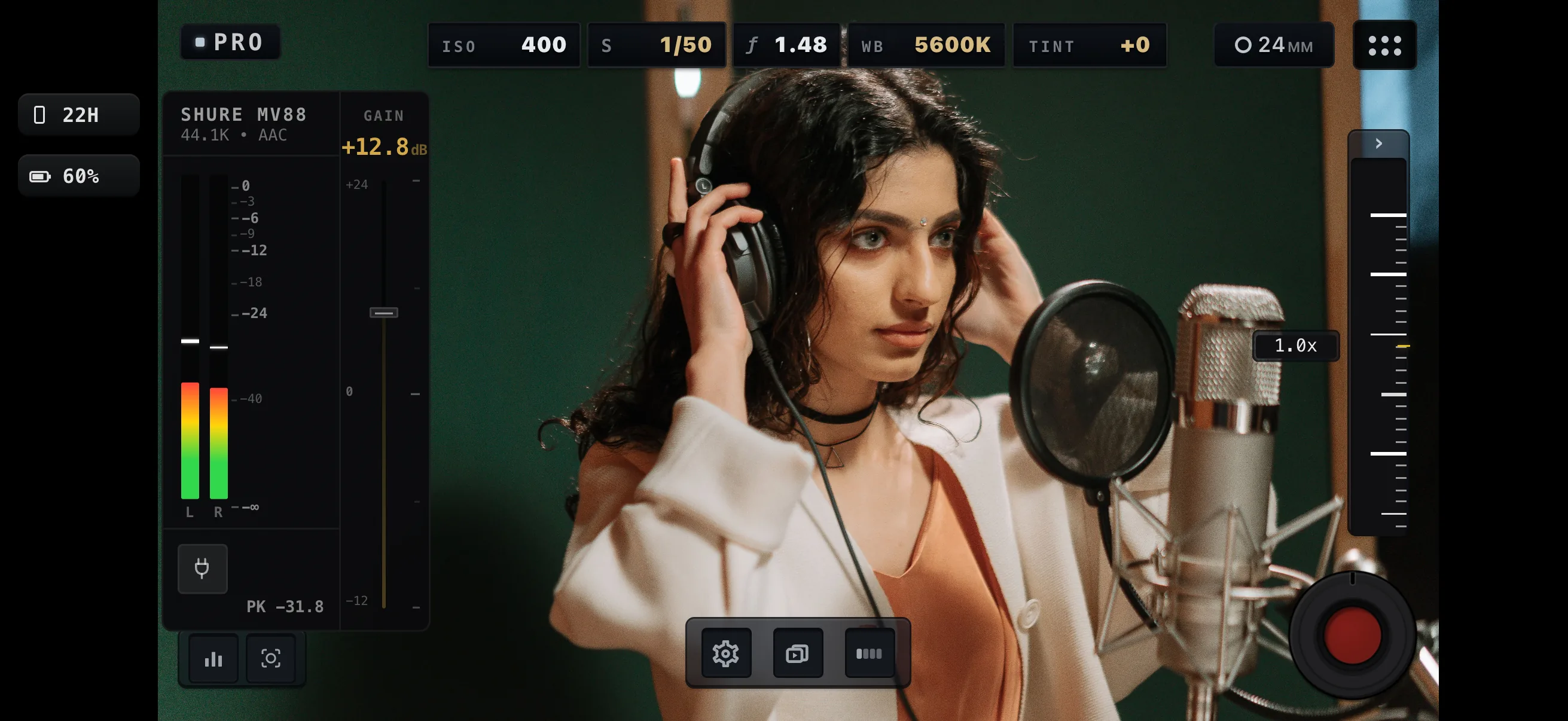 MoviePro in Pro mode, landscape, framing a vocalist in headphones at a studio microphone. The expanded audio panel names the connected microphone — Shure MV88, 44.1K, AAC — with input gain at +12.8 dB, live left and right meters and a peak reading, beside ISO, shutter, aperture, white balance and tint.