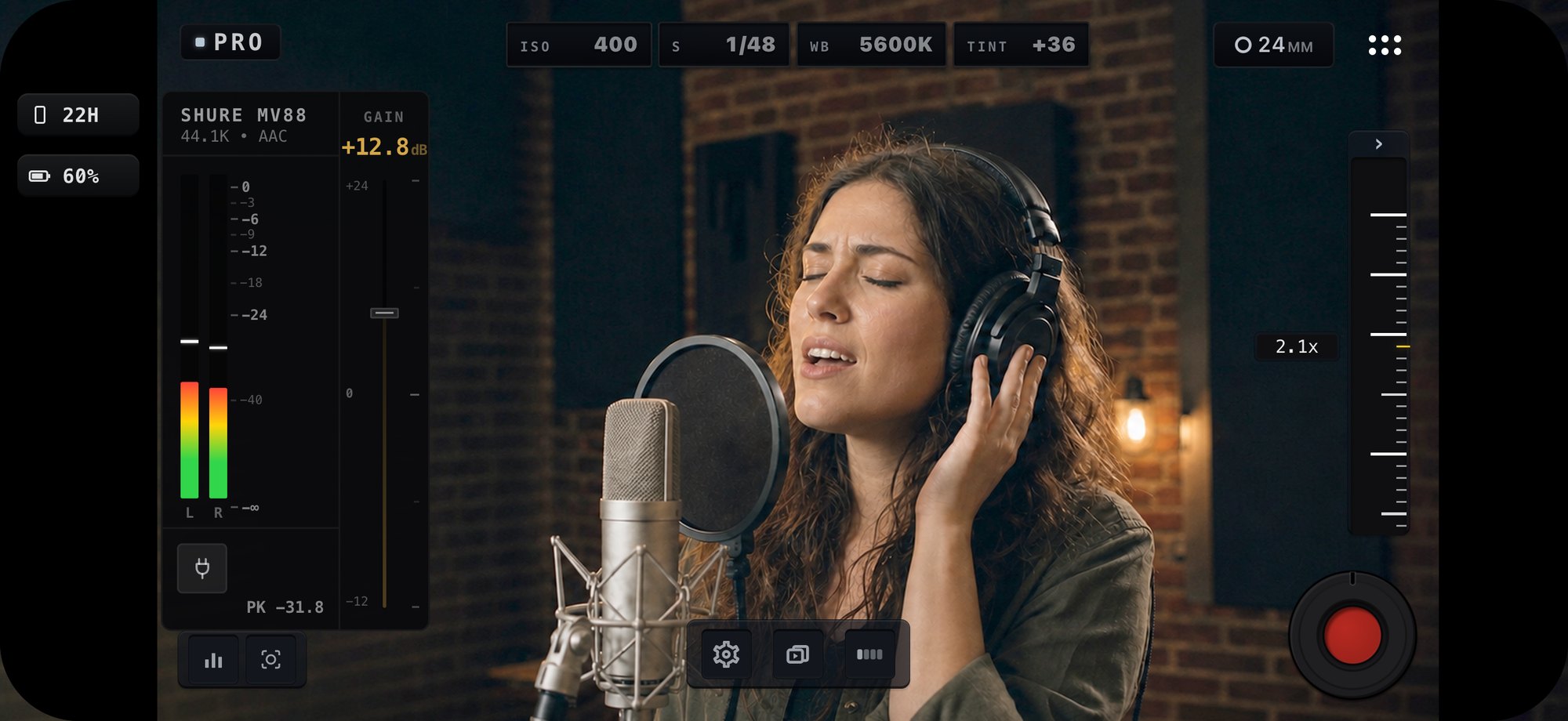 MoviePro in Pro mode, landscape, recording a singer at a condenser microphone in a brick-walled studio. The audio panel names the connected microphone — Shure MV88, 44.1K, AAC — with input gain at +12.8 dB, live left and right meters and a peak reading, beside ISO, shutter, white balance and tint.